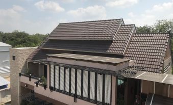 a building with a black roof and a brown tiled roof , surrounded by trees and other buildings at The Sept Korat