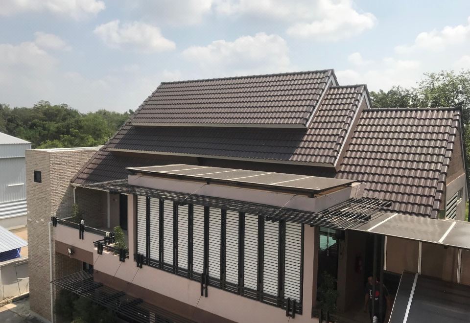 a building with a black roof and a brown tiled roof , surrounded by trees and other buildings at The Sept Korat