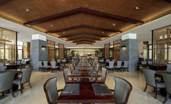 The restaurant features spacious tables and chairs arranged in the center, creating an open concept dining area at Pullman Oceanview Sanya Bay Resort & Spa