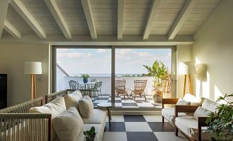 a living room with a view of the ocean , featuring a checkered floor and white furniture at Seebay Hotel