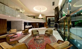 a luxurious hotel lobby with a large chandelier hanging from the ceiling , multiple couches , and a staircase leading to an upper level at Majestic Palace Hotel