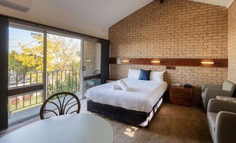 a bedroom with a large bed , a dining table , and a sliding glass door leading to a balcony at Colac Mid City Motor Inn
