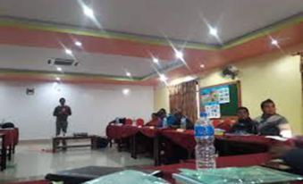 a classroom setting with several people sitting at desks and a teacher standing behind them at Suva Hotel