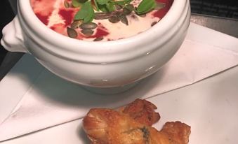 a white bowl filled with red soup and a piece of fried chicken on a white plate at The White Hart Hotel