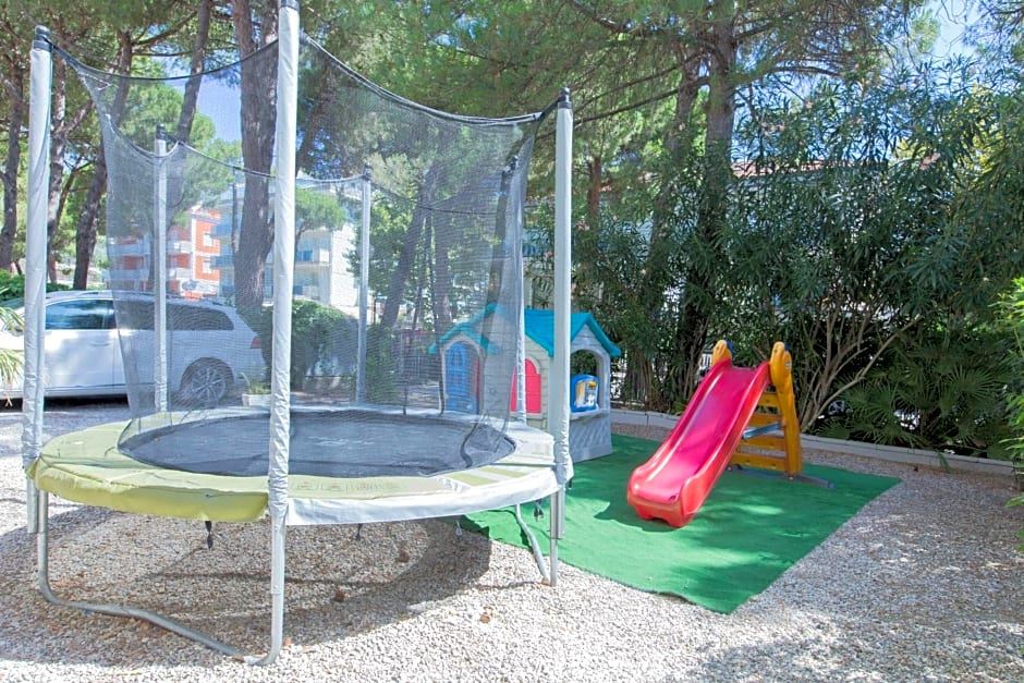a backyard with a trampoline , a slide , and a playhouse , surrounded by trees and grass at Hotel New York