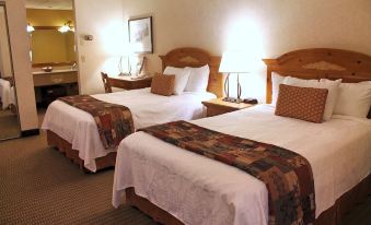 a hotel room with two beds , each made up with white sheets and a floral comforter , accompanied by nightstands and lamps at The Inn at Holiday Valley