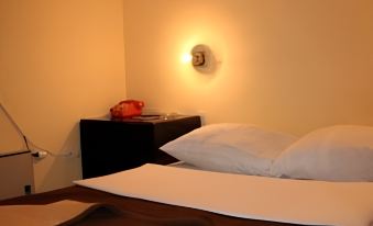 a small bedroom with a bed , a nightstand , and a lamp on the wall , illuminated by a light at Zlatibor Hotel