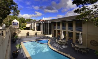 a large swimming pool is surrounded by lounge chairs and umbrellas in a courtyard setting at Twin Towers Inn