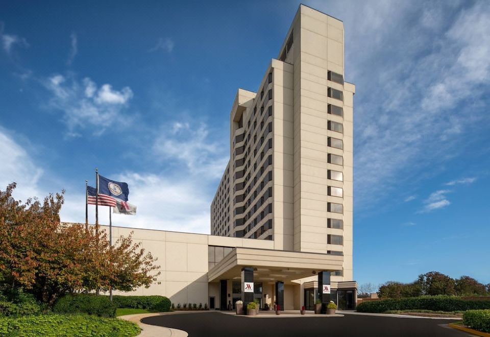 a tall hotel building with a flagpole in front of it , surrounded by grass and trees at Tysons Corner Marriott