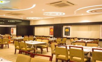 a well - lit restaurant with multiple dining tables and chairs arranged for a large group of people at Hotel Celebration