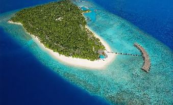 a tropical island with a white sandy beach and a walkway leading to the entrance of it at Filitheyo Island Resort