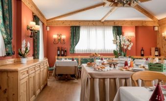 a well - decorated dining room with wooden furniture , including a dining table and chairs , as well as a tv mounted on the wall at Hotel Cristallo