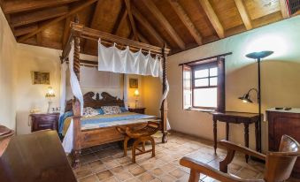 a cozy bedroom with a wooden bed , a chair , and a dresser , along with a window and a lamp at Hotel Rural Restaurante Mahoh