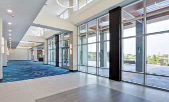 a large , modern hotel lobby with multiple floors , glass doors , and a carpeted floor at Embassy Suites by Hilton Plainfield Indianapolis Airport