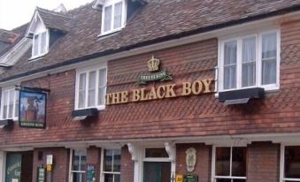 "a brick building with a sign that reads "" the black boy "" on it , located in a city" at The Westgate