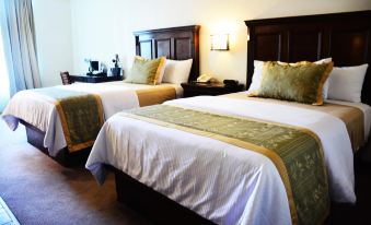 two beds with white linens and green accents are next to each other in a room at Hotel San Carlos Tequisquiapan