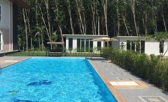 a large swimming pool is surrounded by lush green trees and a building with a white roof at Pool House Lanska