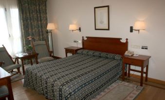 a hotel room with a king - sized bed , two lamps , and a framed picture on the wall at Pousada de Portomarin