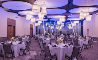 a large banquet hall with round tables and chairs , white tablecloths , and blue lights hanging from the ceiling at The Hotel at Oberlin
