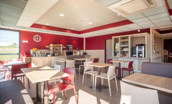 a modern cafe with red walls , wooden tables , and chairs , as well as a kitchen area at Ace Hotel le Mans