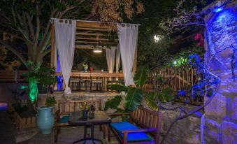 a wooden structure with a white canopy is lit up at night , next to a table and chairs at Dali