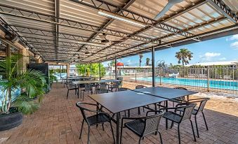 an outdoor patio with a ping pong table and chairs , providing a comfortable space for outdoor dining and relaxation at Carnarvon Motel