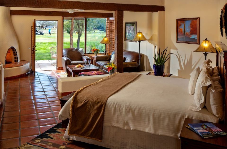 a spacious bedroom with a large bed , a couch , and a view of a golf course outside the window at Tubac Golf Resort & Spa