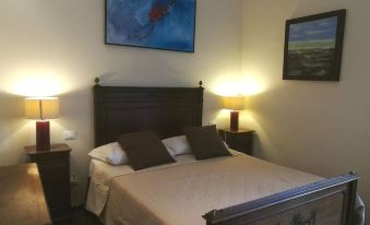 a well - decorated bedroom with a wooden bed , two nightstands , and a painting on the wall at Legacy