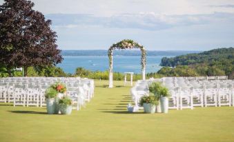a wedding ceremony is taking place on a grassy field with rows of white chairs set up for guests at Agaming Golf Resort