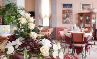 a dining room with a table set for a meal , featuring a bouquet of flowers on the table at Hotel Jasmine