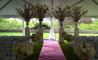 a beautifully decorated outdoor wedding venue with multiple flower arrangements , tables , and chairs set up for a celebration at The Castle at Skylands Manor