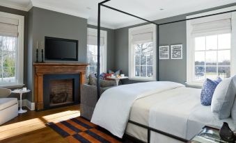 a cozy bedroom with a large bed , a television , and a fireplace , along with some decorative elements at Topping Rose House