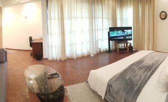 a large bedroom with hardwood floors , a king - sized bed , and a flat - screen tv mounted on the wall at Gardens Lodge