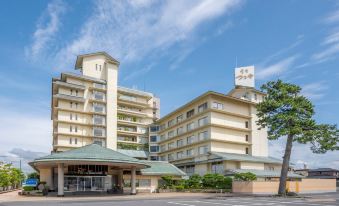 a modern hotel building with multiple floors , surrounded by trees and a clear blue sky at Kaike Tsuruya