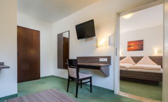 a hotel room with a bed , desk , chair , and television mounted on the wall at Hotel zur Post