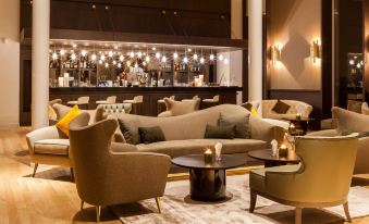 a modern lounge area with a bar and couches , creating a cozy and inviting atmosphere at AC Hotel Paris le Bourget Airport