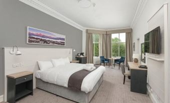 a large bed with white linens is in a room with a window and chairs at The Tarbet Hotel