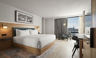 a modern hotel room with a large bed , white bedding , and a view of the city through a window at Hotel Moco Valleyfield