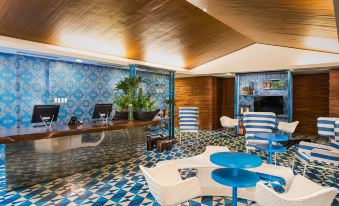 a modern lounge area with blue and white furniture , a checkered floor , and large windows at Astoria Palawan