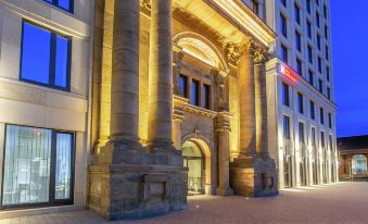 a grand entrance to a building with stone pillars and arches , lit up by warm lights at night at Hilton Garden Inn Mannheim