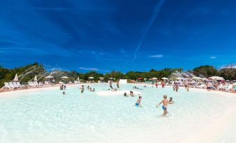 a group of people enjoying a sunny day at a water park , playing in the pool and splashing in the water at Hu Montescudaio Village