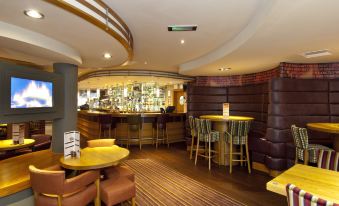 a well - lit restaurant with various dining tables and chairs , as well as a bar area at Premier Inn Burgess Hill