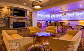 a cozy living room with various seating options , including couches and chairs , as well as a television mounted on the wall at Best Western Plus Butte Plaza Inn