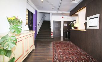 a hotel lobby with a check - in desk , a staircase leading to the second floor , and a rug on the floor at Hotel Napoleon