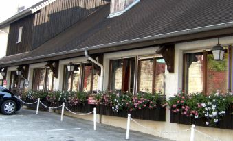 a building with flowers in flower boxes and a white fence around the entrance , creating a welcoming atmosphere at La Cascade