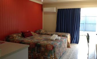 a hotel room with three beds , one on the left , one in the middle , and one on the right at Emu Park Motel