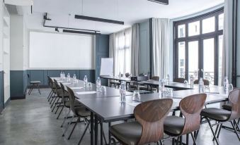 a conference room with a long table , chairs , and a projector screen , set up for a meeting or presentation at Hotel Bachaumont