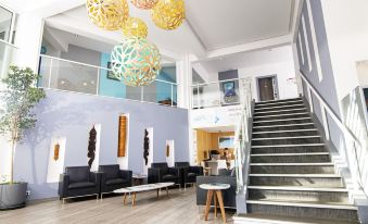 a modern hotel lobby with a staircase leading to the second floor , where several people are sitting and enjoying the space at Hotel Beaurivage