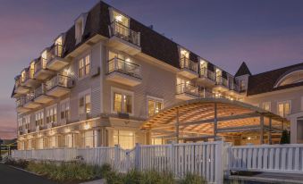 a large white building with multiple balconies and a covered walkway is lit up at night at Nantasket Beach Resort