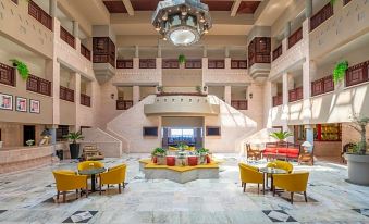 a spacious , well - lit atrium with multiple floors and high ceilings , surrounded by yellow and red chairs at Grand Mercure Petra